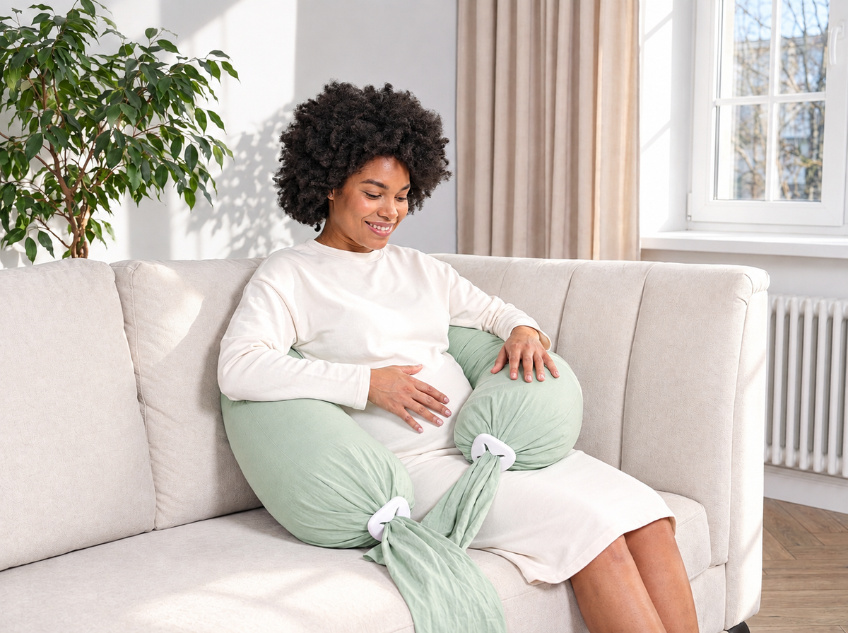 Femme assise sur un canapé avec un coussin de grossesse vert