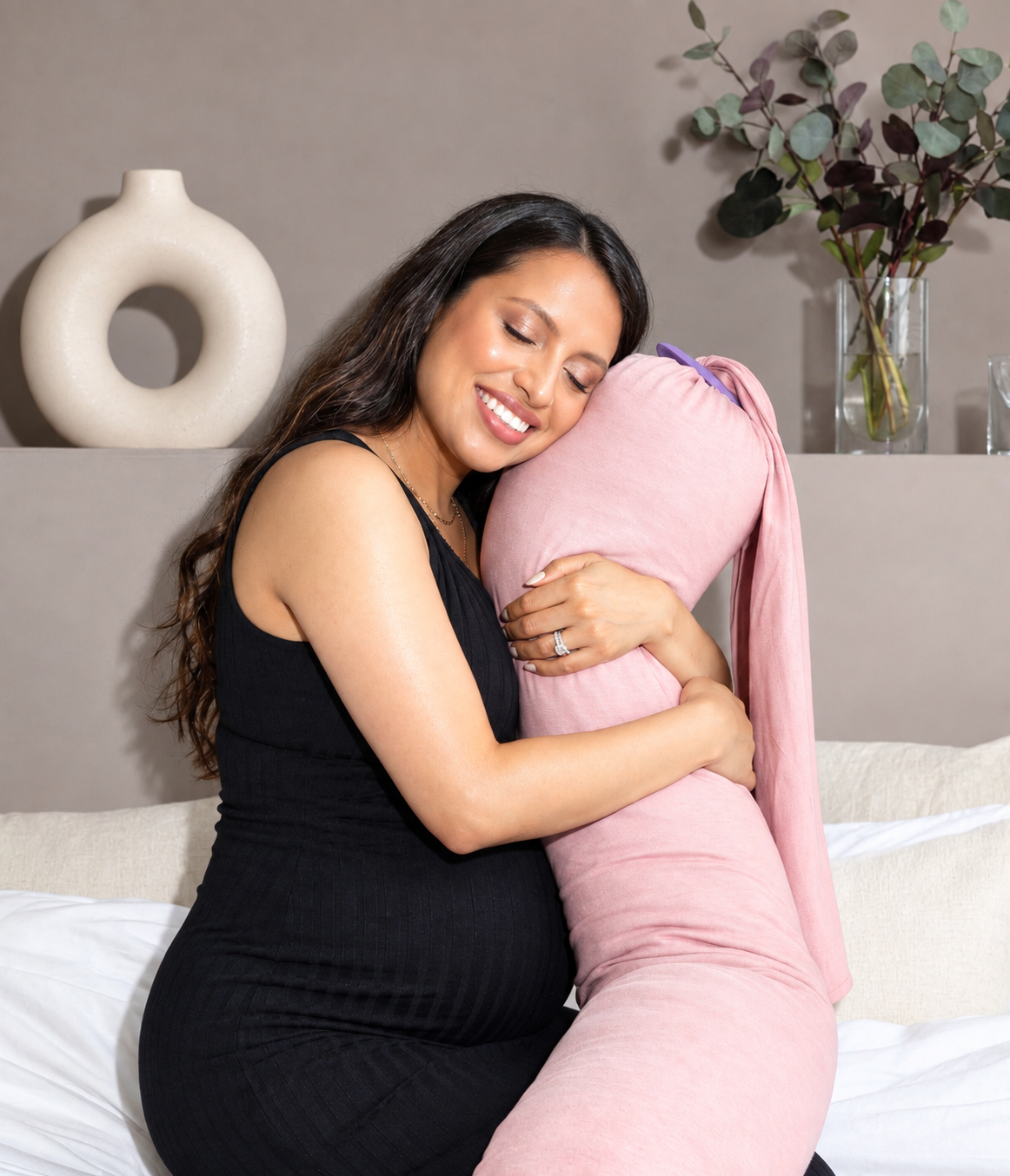 Femme enceinte serrant un coussin de grossesse et d'allaitement rose dans ses bras