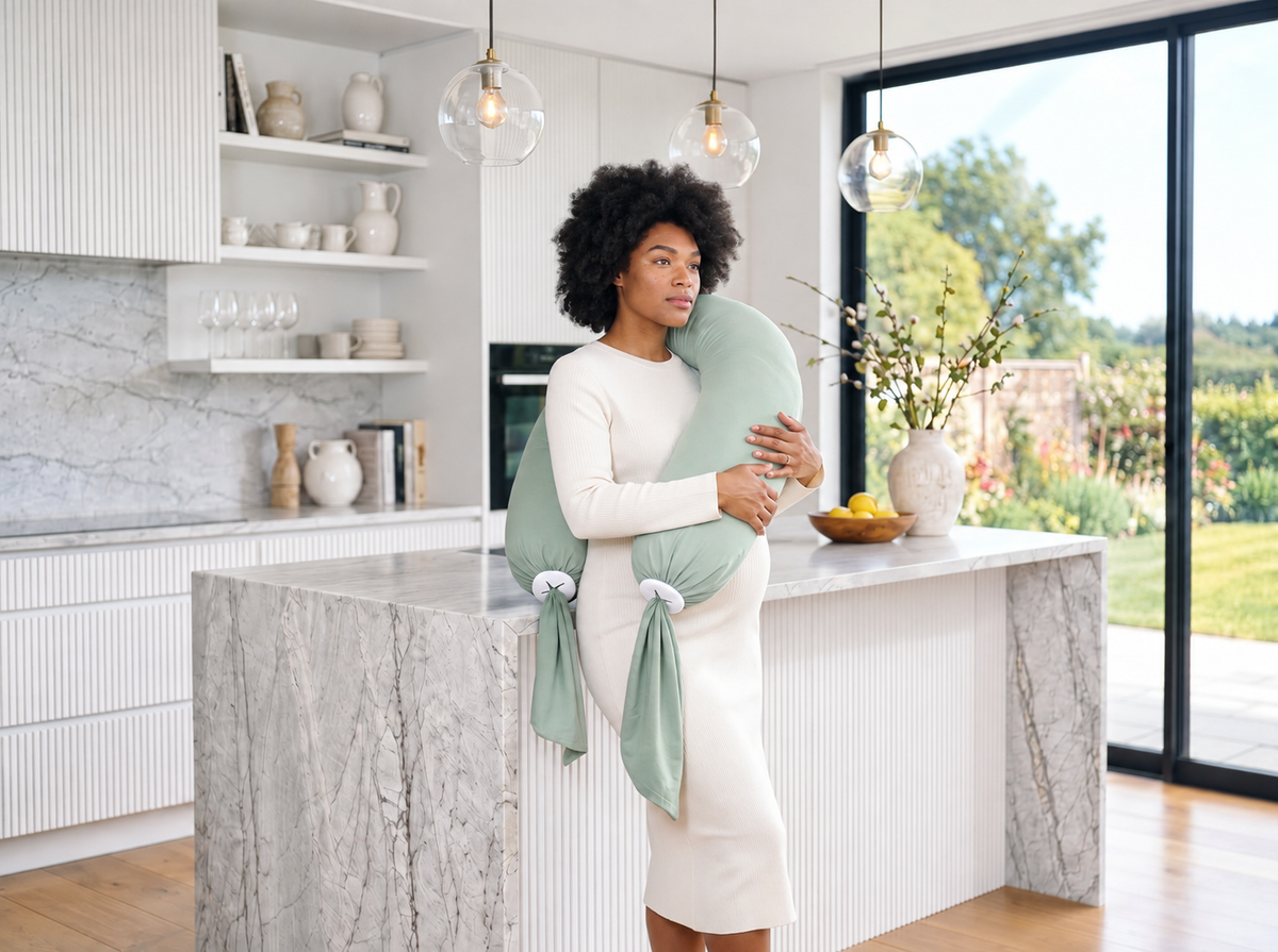 Femme debout dans une cuisine avec un coussin de grossesse vert