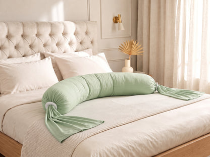Coussin de grossesse et d'allaitement vert posé sur un lit